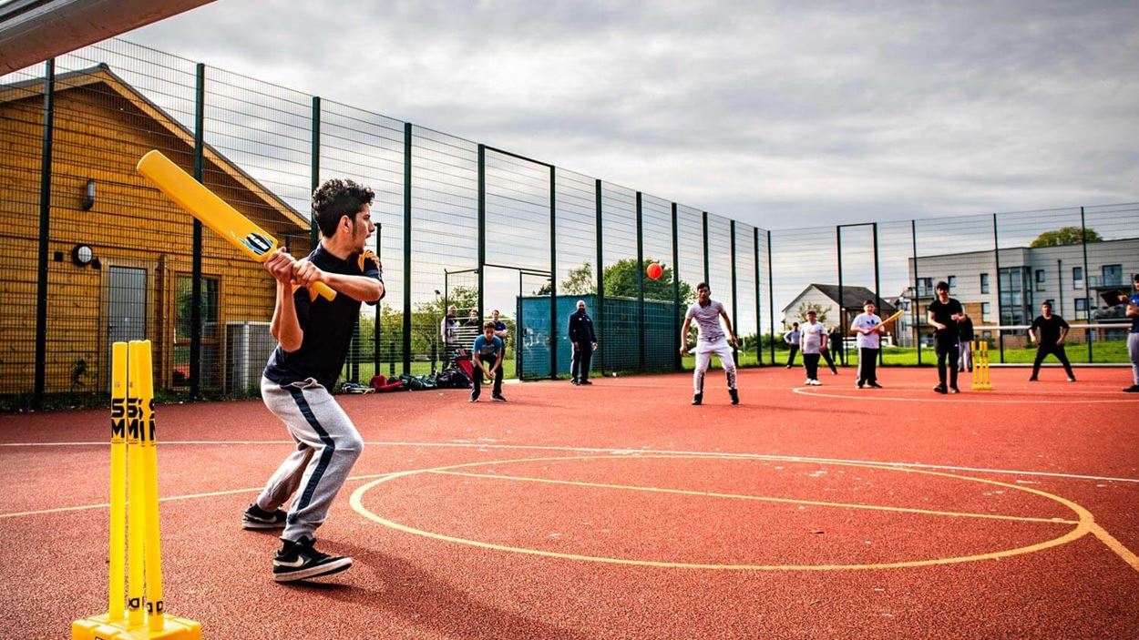 Player with arm cocked back ready to strike the circket ball